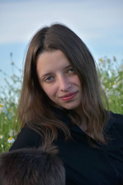 Siyah elbiseli bir kız çimlerin üzerinde oturuyor.,