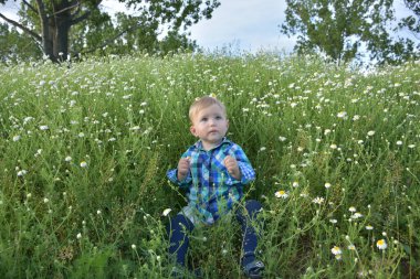 Çocuk çimenlerde oturuyor.