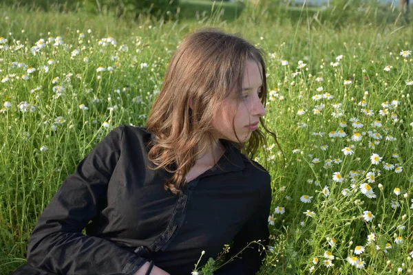 黒いドレスを着た女の子が草の上に座って — ストック写真