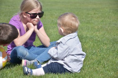 Cute kids sitting on green grass enjoying sun