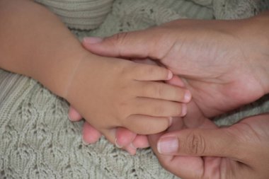 close up of mother hands holding her baby's hand. closeup.