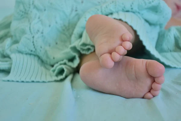 Selective Focus Barefoot Child Relaxing Covered Mint Colored Knit Fabric — стоковое фото