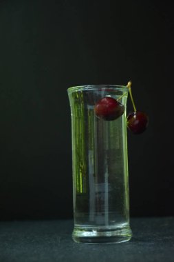 Koyu arkaplanda cam kaplı kirazlı içecek.