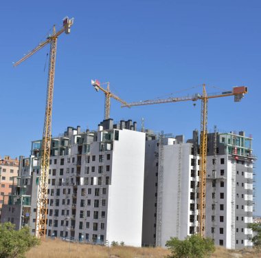 construction cranes and buildings under blue sky