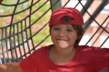 Boy in red outfit having fun playing outdoors on playground