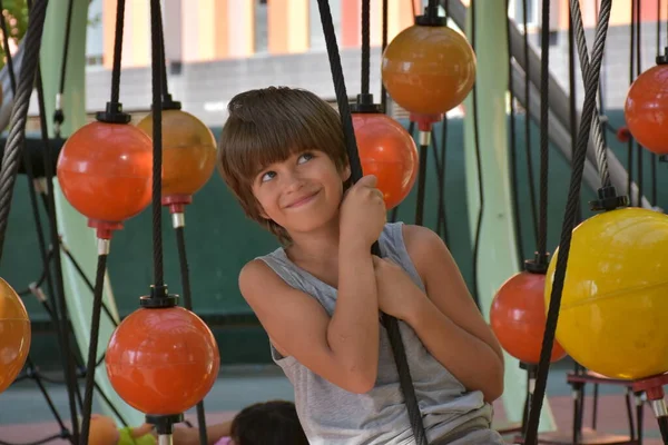 Χαριτωμένο Αγόρι Στηρίζεται Στην Παιδική Χαρά Κρέμονται Πλαστικές Μπάλες — Φωτογραφία Αρχείου