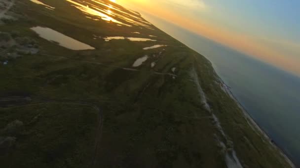 FPV Renndrohne Luftaufnahme der Insel Dzharylgach bei Sonnenuntergang. Eine breite Küste, viele Seen, ein alter und neuer Leuchtturm und ein Schwarzes Meer — Stockvideo