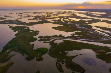 Parlak günbatımındaki bataklığın insansız hava aracı görüntüsü. Göller ve Bataklıklar arasındaki Aspalt Yolu