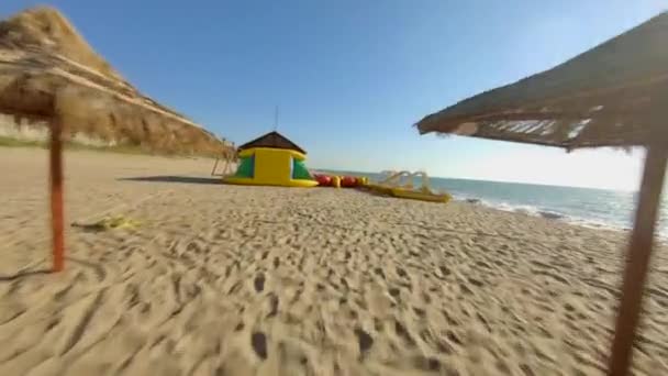 FPV carreras Drone Shot Flyby en la playa del Mar Negro en Griborka, cerca de Odessa. Beach Resort con sombrillas de paja — Vídeos de Stock