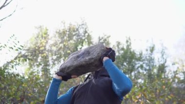 Dreadlocks 'lu güçlü gri saçlı adam dışarıda taşla egzersiz yapıyor. Ağır Taşı Bir Sokakta İtin. Şehir sokak çalışması.