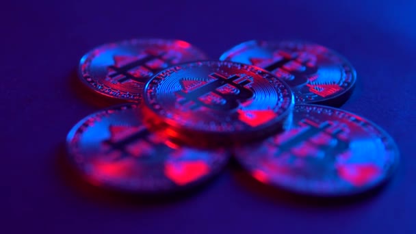 Ψηφιακό Bitcoin νόμισμα περιστρέφεται με ένα άλλο Bitcoins στη μαύρη επιφάνεια. Ροζ και μπλε νέον φως — Αρχείο Βίντεο