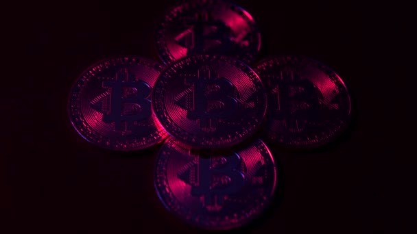 Moneda digital Bitcoin gira con otro Bitcoins en la superficie negra. Luz de neón roja y azul — Vídeo de stock