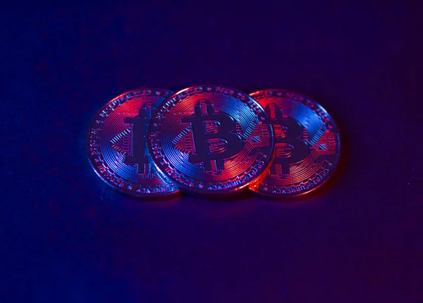 Las monedas de Bitcoin están en una superficie oscura. Luz de neón púrpura y rosa — Foto de Stock
