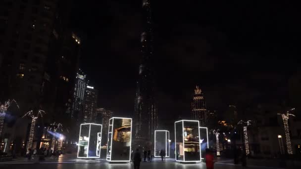 Dubaj, SAE 2020: Na nábřeží jsou umístěna krásná valivá zrcadla designéra s Burjem Khalifou na pozadí. Laserová show v noci v Dubaji — Stock video
