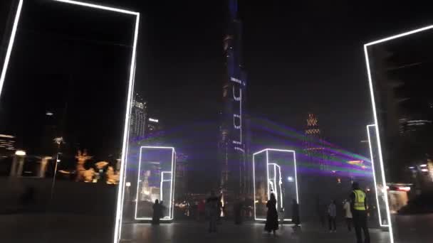 Dubaj, SAE 2020: Na nábřeží jsou umístěna krásná valivá zrcadla designéra s Burjem Khalifou na pozadí. Laserová show v noci v Dubaji — Stock video