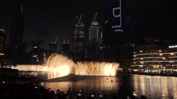 DUBAI, SAE - FEB 2020: Tančící fontány v noci. Dubajská taneční fontána je největší svého druhu na světě: její vodní trysky, pohybující se do rytmu hudby a jsou osvětleny barevnými světly a — Stock video