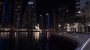 BAE, DUBAI - Ocak 2020: Dubai Marina gökdelenleri, binalar ve suda yansıyan hareket eden teknelerle gökyüzü silueti. Gerçek zamanlı çekim.