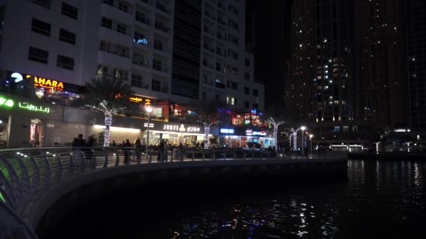 UAE, DUBAI - JANUARY 2020: Dubai Marina skyline with illuminated sky scrappers, buildings and moving boats showing reflection on water. Real time shot — Vídeo de Stock
