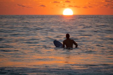 Silhouette of Surfer waiting on the line up for a wave at sunrise or sunset. clipart