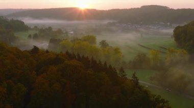 Lüksemburg 'daki sonbahar renkli ormanların ve vadilerin üzerinde sabah sisiyle kaplı hava aracı Sunrise View. 4k drone görüntüsü