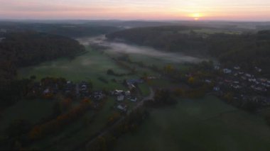 Lüksemburg 'daki sonbahar renkli ormanların ve vadilerin üzerinde sabah sisiyle kaplı hava aracı Sunrise View. 4k drone görüntüsü