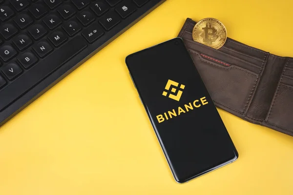 Логотип Binance на смартфоне с кошельком, биткойном и клавиатурой — стоковое фото