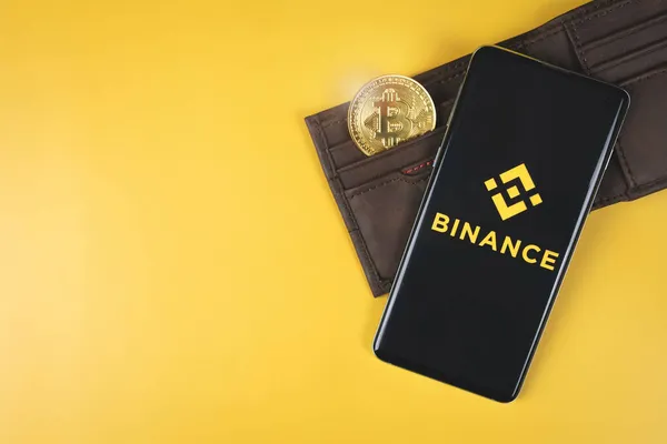 財布とBitcoinを備えたスマートフォンのBinanceロゴ — ストック写真
