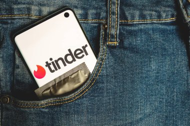 Pantolon cebinde Tinder logosu ve prezervatif olan telefon.