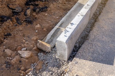 Beton kaldırım döşemesi yol inşaatında çalışıyor. Dizgi seviyesi rehberi.