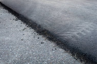 Taze siyah ve eski gri asfalt katmanları yol yüzeyi dokusu köşegen çizgisine yakın çekim.