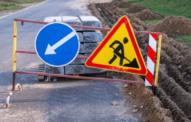 İnşaat üçgeni yol işareti ve mavi ok işareti altında.