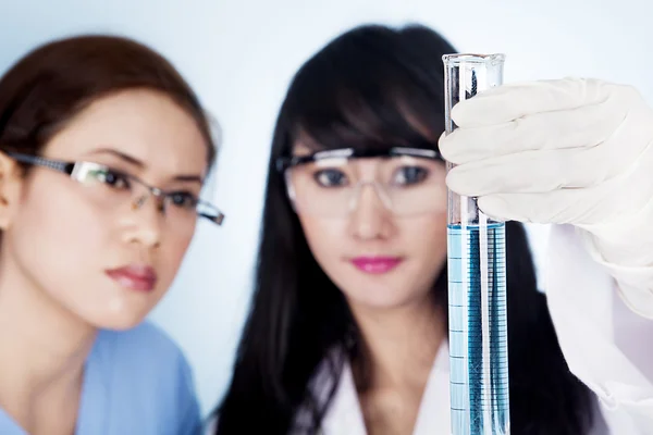 Equipe de pesquisa científica feminina com solução azul clara em laboratório — Fotografia de Stock