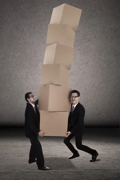 Týmová práce se snaží vyvážit těžké krabiceチームワークは重い箱をバランスしようとすると — Stock fotografie