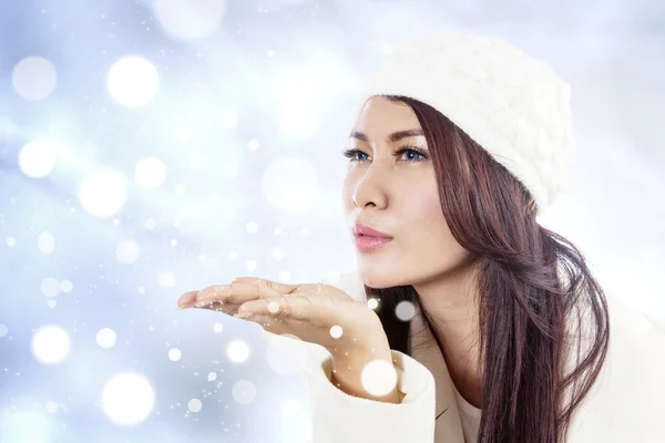 Schöne Dame bläst Schneeflocken auf blauen defokussierten Lichtern — Stockfoto