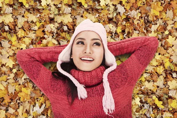 Glückliche Frau, die auf Herbstblättern liegt — Stockfoto