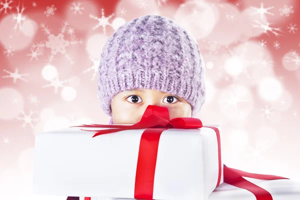 Niño detrás de los regalos en rojo luces desenfocadas fondo —  Fotos de Stock