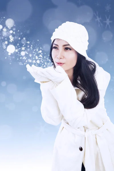 Beautiful woman blowing snowflakes — Stock Photo, Image