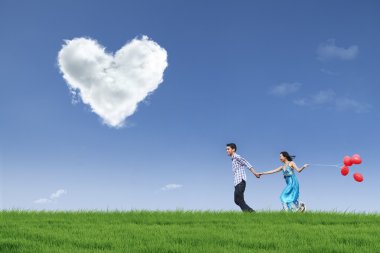 Happy couple running in field with balloons clipart