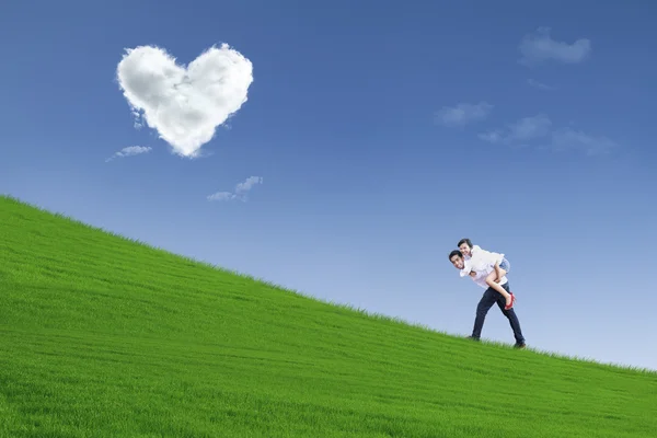 Menina em piggyback passeio sob nuvens de coração — Fotografia de Stock