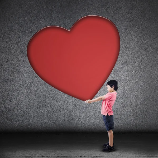 Muchacho sostiene gran signo de corazón en blanco — Foto de Stock