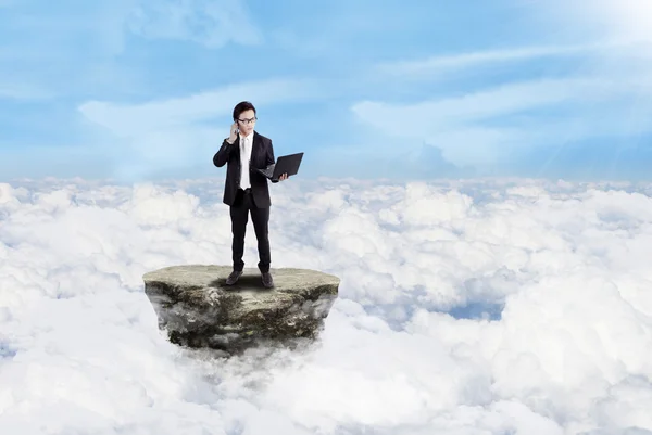 Бизнесмен, работающий с ноутбуком над облаками — стоковое фото