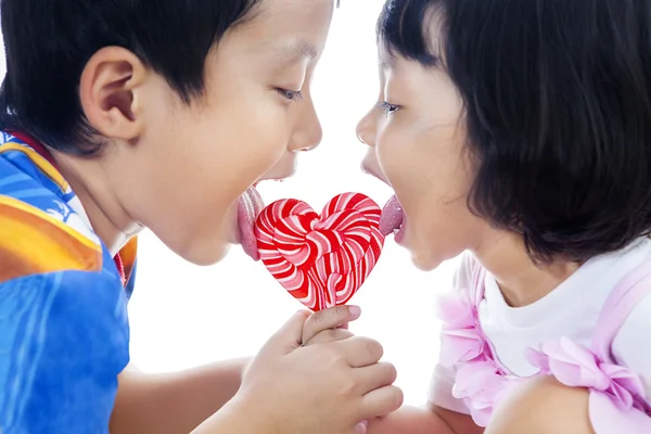 Cute siblings lick lollipop — Stock Photo, Image