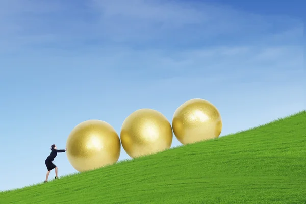Бизнесмен толкает золотые яйца на холм — стоковое фото