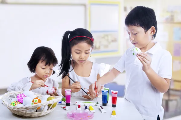 Enfants peignant des œufs de Pâques en classe d'art — Photo