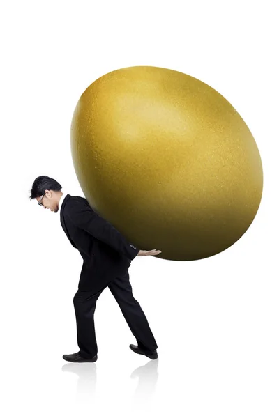 Empresário carrega enorme ovo de ouro — Fotografia de Stock