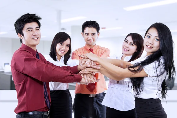 Business team joining hands in office — Stock Photo, Image