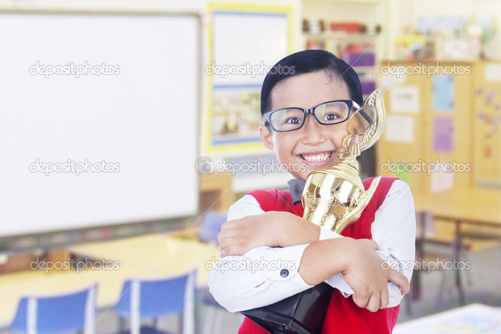 Boy holds trophy at school