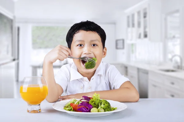 Menino comendo brócolis em casa — Fotografia de Stock