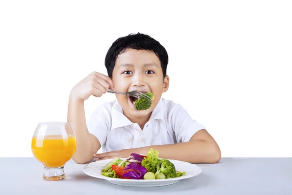 Boy eating broccoli - isolated — Stock Photo, Image