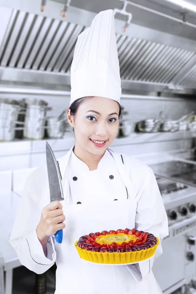Koch hält Messer und Dessert in der Hand lizenzfreie Stockbilder